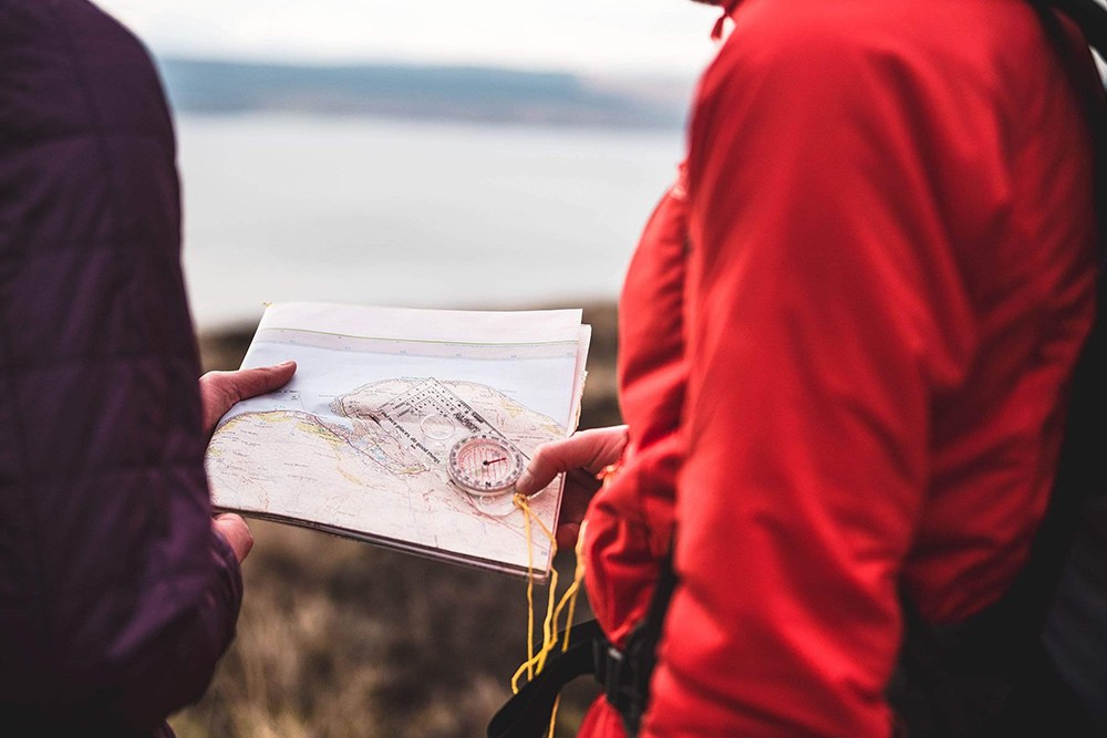 Two hikers study a compass and map in the UK outdoors