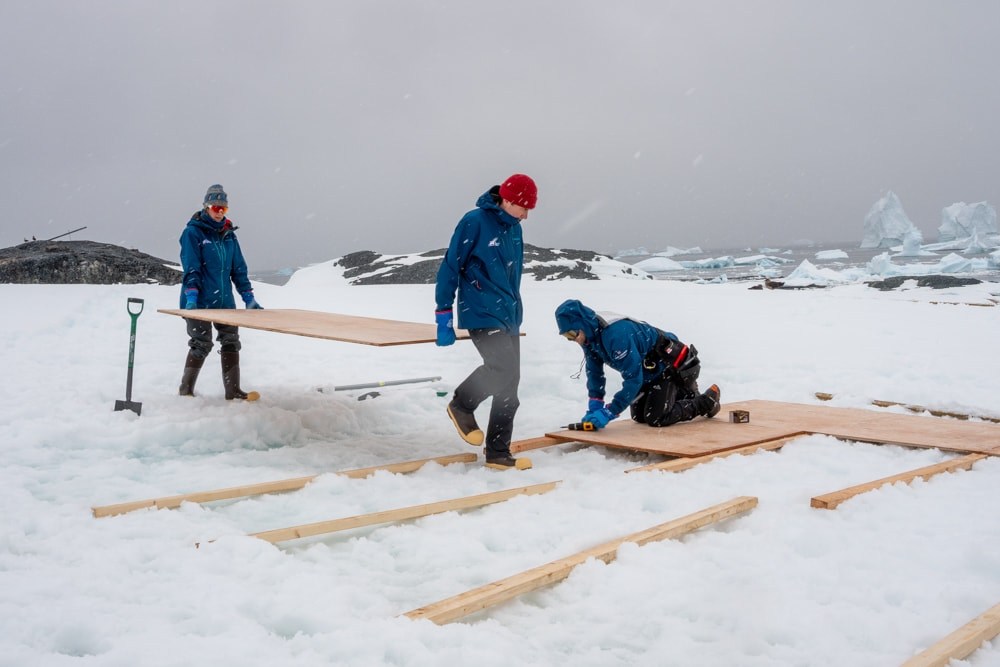 team members lay boards for camp