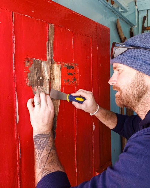 A carpenter works on a door a Port Lockroy